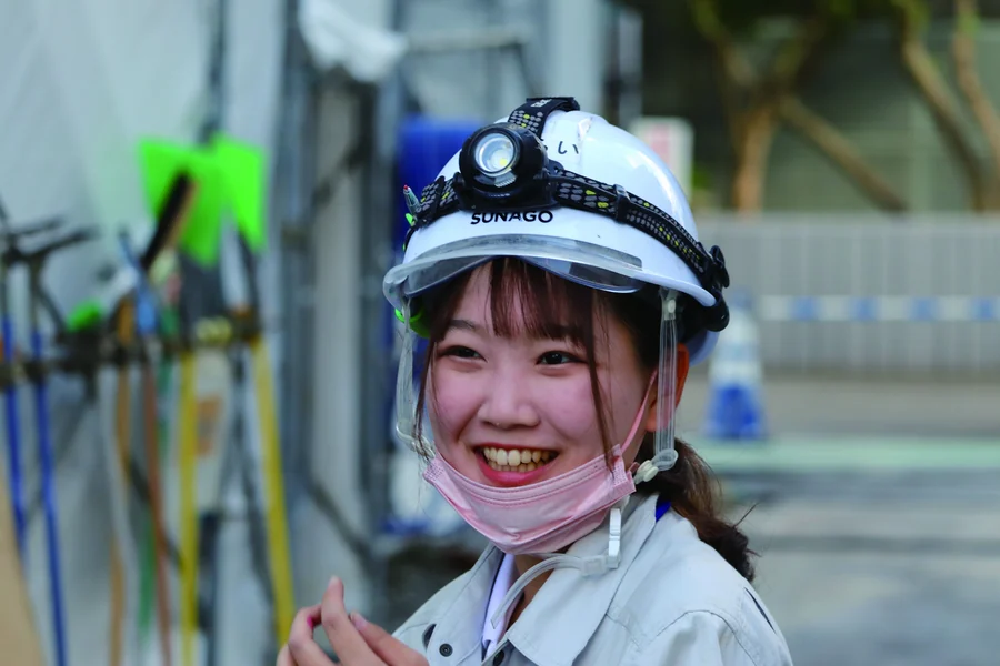 ヘルメット姿で建設現場に立つ女性