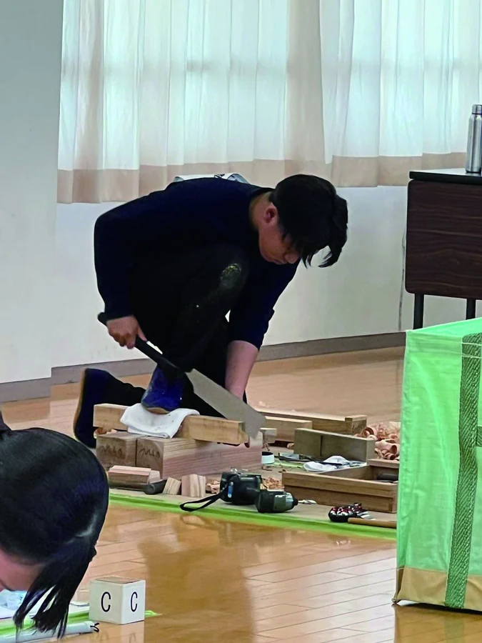 のみと木づちで木材を加工する建築科の生徒