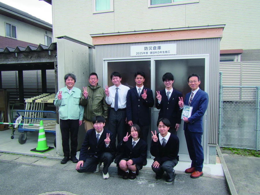 完成した防災倉庫の前で記念撮影する生徒と先生