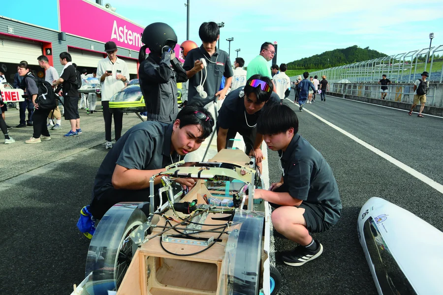 サーキットで電気自動車を調整する生徒たち