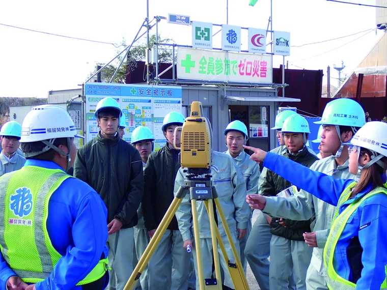 建設現場で測量機器を使った見学に参加する生徒たち