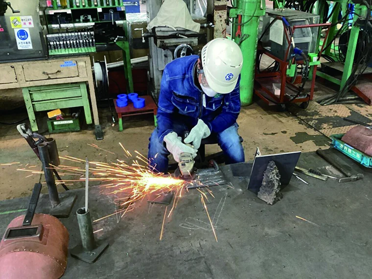 工場で金属を切断する作業を体験する生徒